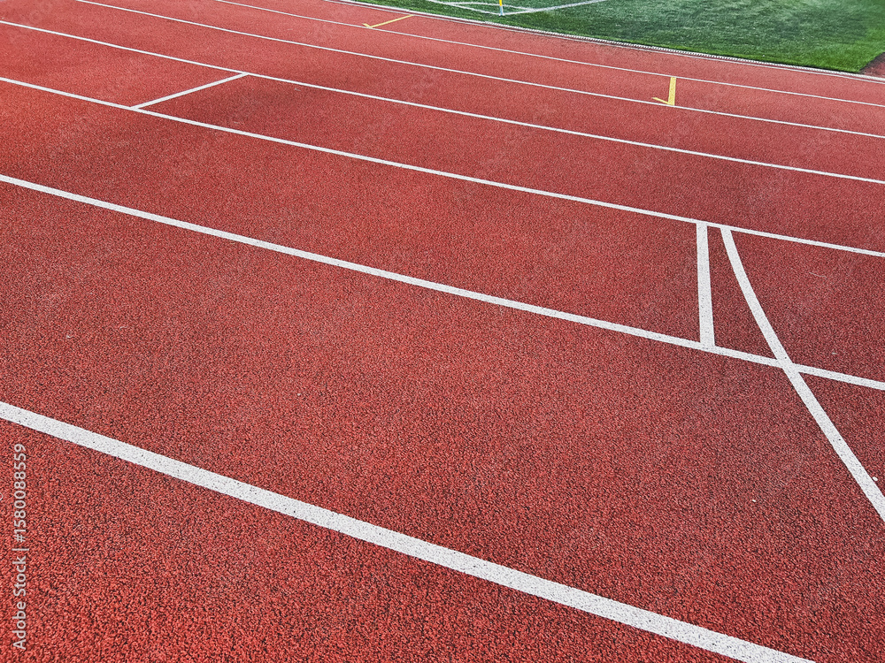 Fototapeta premium Empty red running track with white lines suggesting movement.