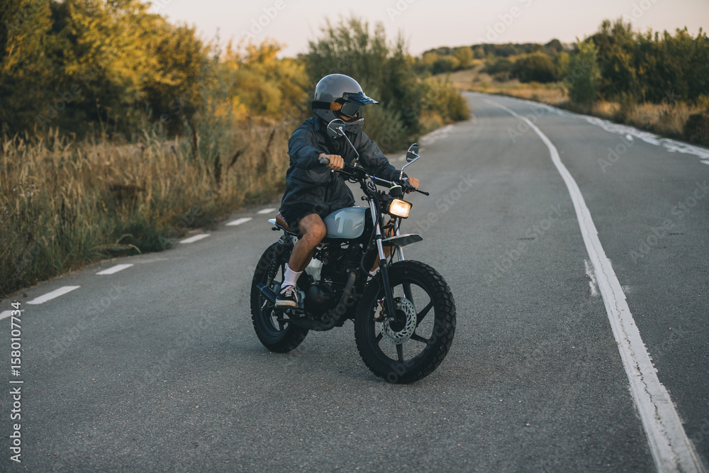 Obraz premium Young motorcyclist riding custom motorcycle on country road