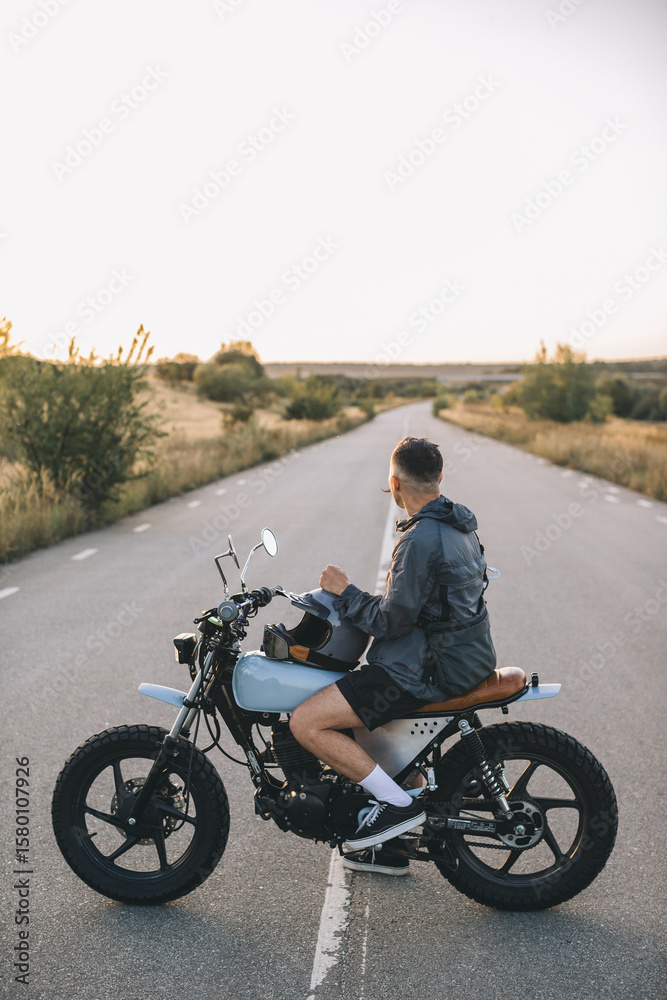 Obraz premium Biker sitting on motorcycle looking at the road ahead