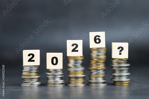 Stack of coins with wooden blocks, symbolizing future financial growth, economic uncertainty, and investment planning for the year 2026
