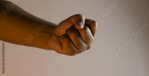 Tableau sur toile Male hand forming a tight fist on white background under warm ambient light, sym