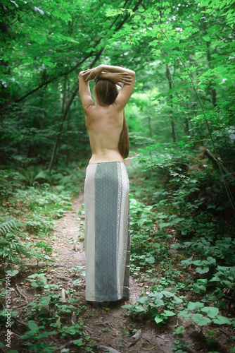 Woman in the forest. View from the back. Enjoying nature.