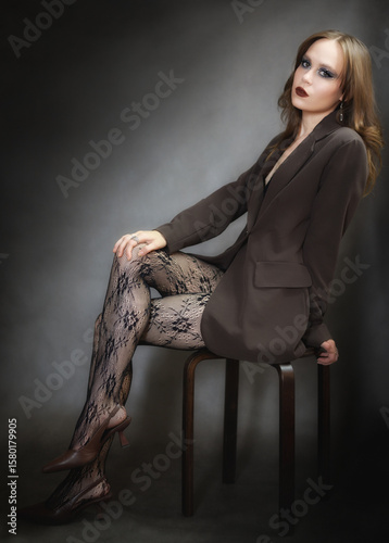 Sensual portrait of young woman in dark suit and fishnet tights.