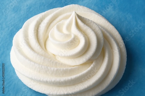 A close-up of a mound of creamy white whipped cream on a smooth blue background