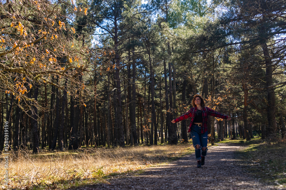 Fototapeta premium Young woman walking in forest feeling freedom and happiness during hiking in nature