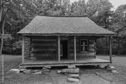 Slika na platnu Black and white photograph of the Carter Shields cabin in Cades Cove, showing the front door, covered porch, and the rocks used to support and level the cabin
