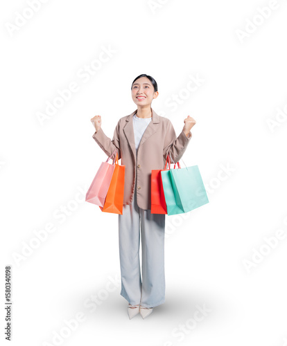 Принти на полотні Full-length portrait of an overjoyed young Asian woman holding shopping bags, looking up hopefully and clenching her fists in a triumphant, celebratory gesture against a png background