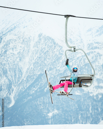 Happy excited woman skier isolated sit on ski resort chairlift wave and enjoy holidays mountain views pose outstretch arms on winter ski vacation outdoors. Xmas holidays and fun in mountains