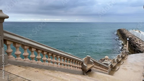Cinematic view of a moody sea framed by the balustrade of Sitges cathedral stairs