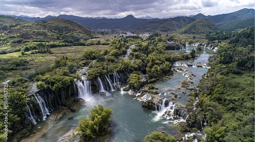 Bird's-eye view of the park's waterfalls, green hills, and idyllic scenery; The wide river flows through lush forests, raindrops falling from high waterfalls, splashes, natural beauty and tranquility.
