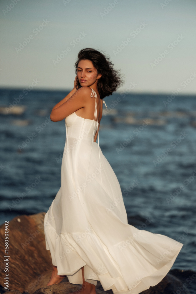 Ocean Breeze Elegance: Woman in White Dress on Coastal Rocks
A woman in a flowing white dress stands gracefully on rugged coastal rocks, with the blue ocean stretching behind her Ocean Breeze Elegance: Woman in White Dress on Coastal Rocks
A woman in a flowing white dress stands gracefully on rugged coastal rocks, with the blue ocean stretching behind her