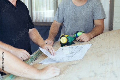men overlooking plans on construction site