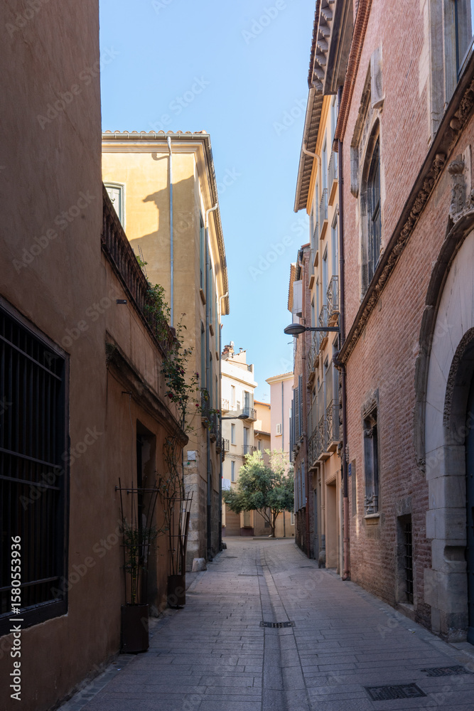 Peaceful narrow alley with historic buildings in Perpignan, France Peaceful narrow alley with historic buildings in Perpignan, France