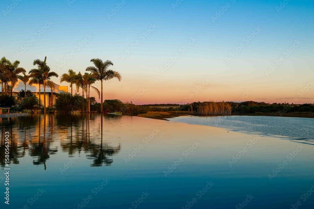 Obraz premium Rural landscape with infinity pool, palm trees and lake
