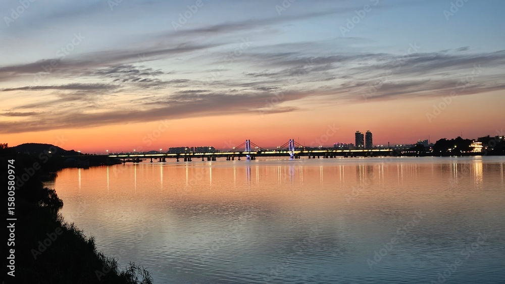 Obraz premium 양화대교를 중심으로 서울 한강에 비친 붉은 노을과 도시의 불빛