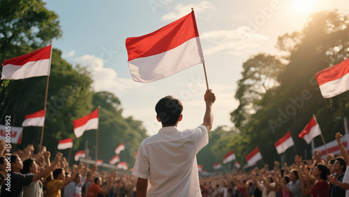 A young man holds the Indonesian flag in a crowd celebrating Independence Day. Patriotic atmosphere with many flags and warm sunset light.