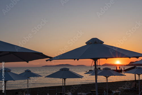 Fototapeta Naklejka Na Ścianę i Meble -  Sunset over beach umbrellas and loungers at Arillas Beach in Corfu, Greece