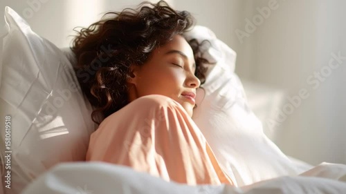 Young woman with curly hair peacefully sleeping on a bed in a sunlit room during the morning