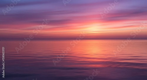 Calm ocean reflecting a vibrant sunset with pink and purple sky colors above