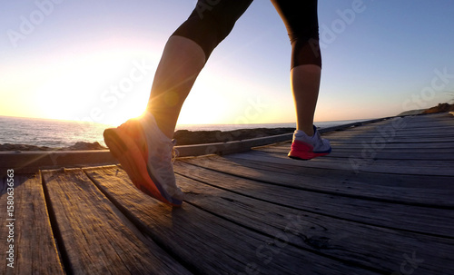 Woman running on boardwalk with lens flare sunrise