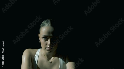 Tight frontal closeup on a woman’s eyes as the camera slowly pulls back, revealing her full face and shoulders while she trains, framed in soft cinematic lighting with a dark, moody background