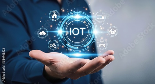 A person holds out their palm displaying a glowing circular interface with the word iot and various connected technology icons