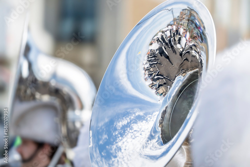 Distorted reflections in glossy bell of tuba during event.