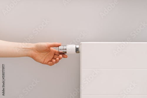 Fotografie Adjusting the temperature on a modern electric heater in a cozy apartment