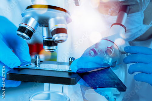 Scientist adjusting microscope and slide in laboratory with blue light for medical research and biotechnology study