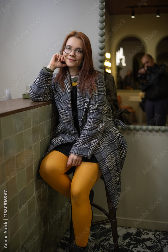 Fototapeta premium Portrait of a young beautiful cheerful red-haired girl in an evening autumn city.