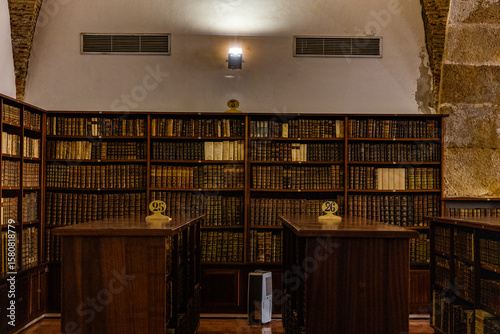 An old library with wooden shelves filled with antique books and numbered desks under soft lighting.