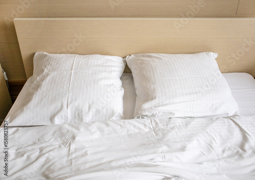 Two white comfortable pillows on the bed in the interior of a hotel room