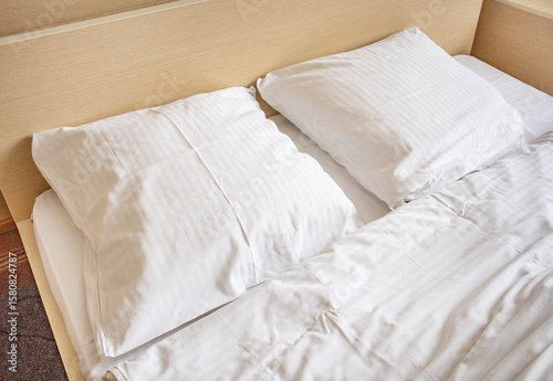 Two white comfortable pillows on the bed in the interior of a hotel room