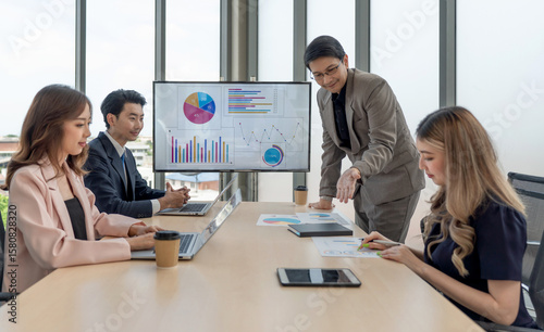 Group of business people are gathered in a meeting room, discussing and sharing ideas around a large conference table.