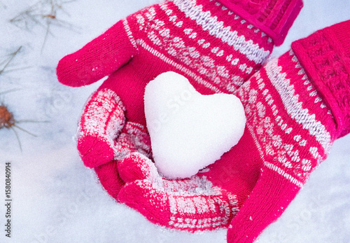 Hands in knitted mittens with heart shaped snow. Winters Day. Valentine's Day