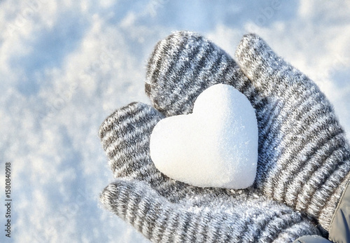 Hands in knitted mittens with heart shaped snow. Winters Day. Valentine's Day
