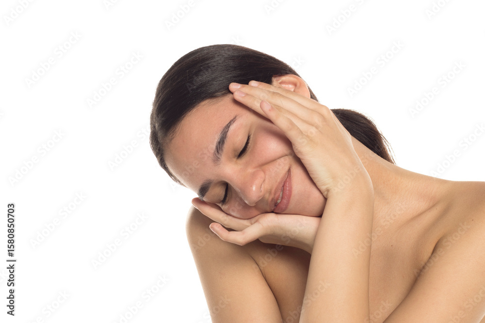 Studio shot of young woman smiling with head tilted and hands framing her face, on white background. Studio shot of young woman smiling with head tilted and hands framing her face, on white background.