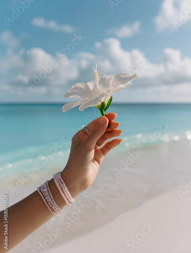 Woman's hand is ho;ding flower near the ocean