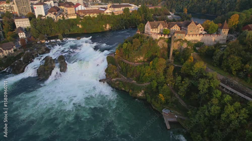 Stunning aerial panorama capturing Rhine Falls, Laufen Castle silhouetted against warm sunset light, showcasing dramatic Swiss landscape with cascading water and historic landmark Stunning aerial panorama capturing Rhine Falls, Laufen Castle silhouetted against warm sunset light, showcasing dramatic Swiss landscape with cascading water and historic landmark