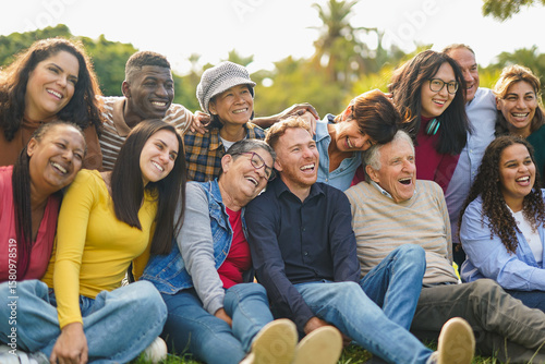 Crowd of happy multiracial people having fun together at city park - Multi generational friends, social gathering and community concept