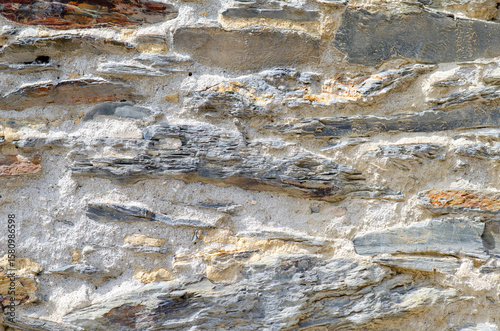 Close-up of an ancient stone wall showing rough slate layers and rustic mortar, perfect for backgrounds, architectural or construction design themes.