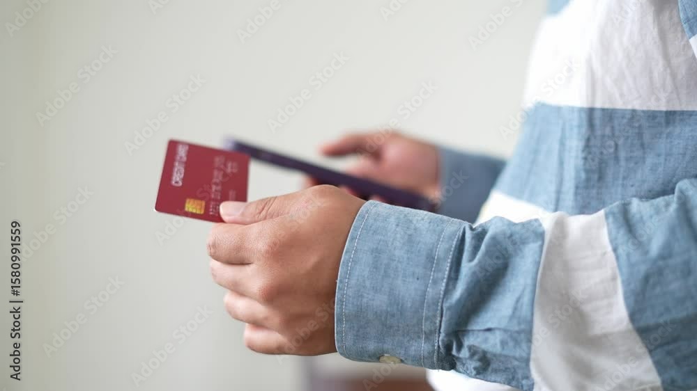 A young asian man is shopping online and holding mobile phone credit bank card payment for online pay, enter secure number authorization buy, purchase shopping internet banking, E-banking app service.