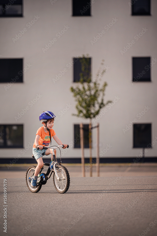 Obraz premium Happy Young Boy Riding Bicycle on Sunny Urban Street
