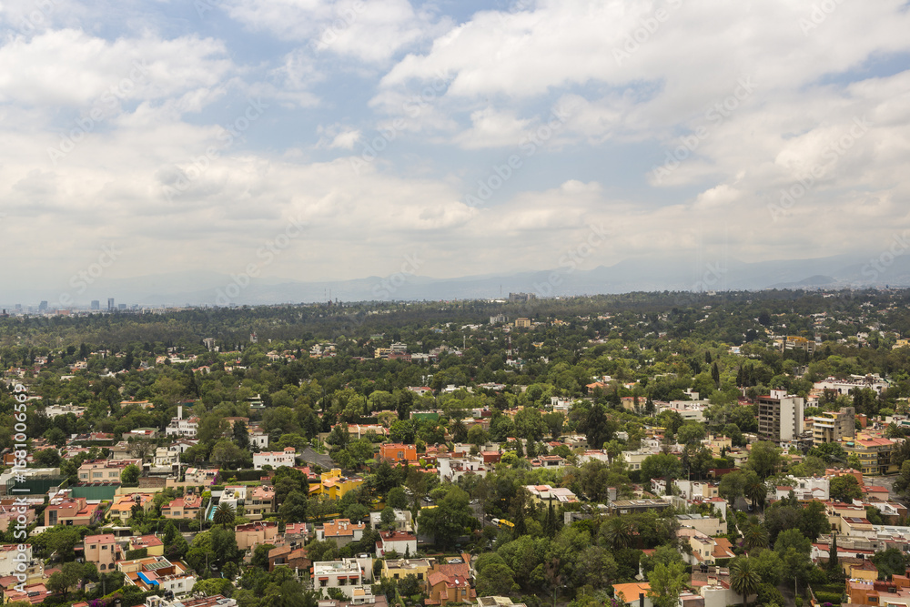 Aerial view of houses nestled among dense trees, creating a vibrant tapestry of green and earthy tones under a cloudy sky, Mexico City, Mexico. Aerial view of houses nestled among dense trees, creating a vibrant tapestry of green and earthy tones under a cloudy sky, Mexico City, Mexico.