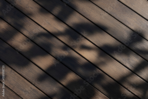 Diagonal wood planks with soft natural tree shadows creating a textured outdoor background