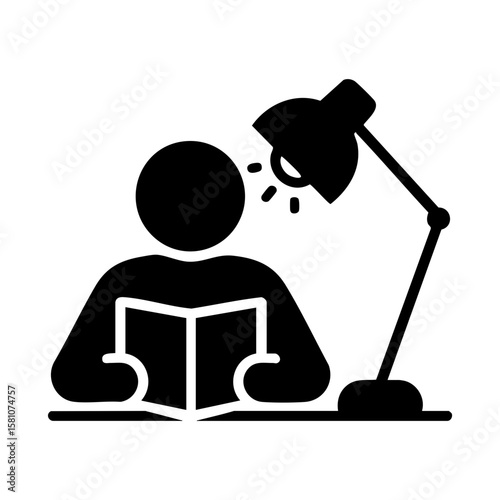 Student reading under desk lamp for night study session concept