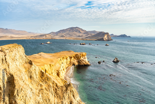 Coastal cliffs and the desert dunes in Paracas National Reserve, Peru. Dramatic landscape with El Playon beach in the distance.