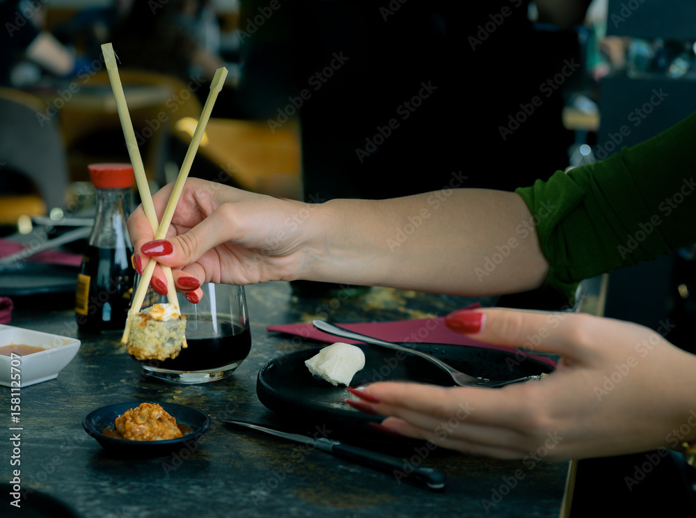 Fototapeta premium A woman is eating sushi with chopsticks