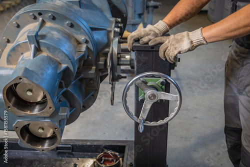 Technician using rotating handle to adjust industrial machine in factory