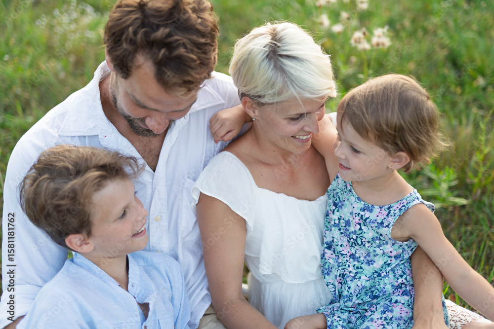 Fototapeta premium Young family enjoying peaceful summer evening outdoors in green summer nature